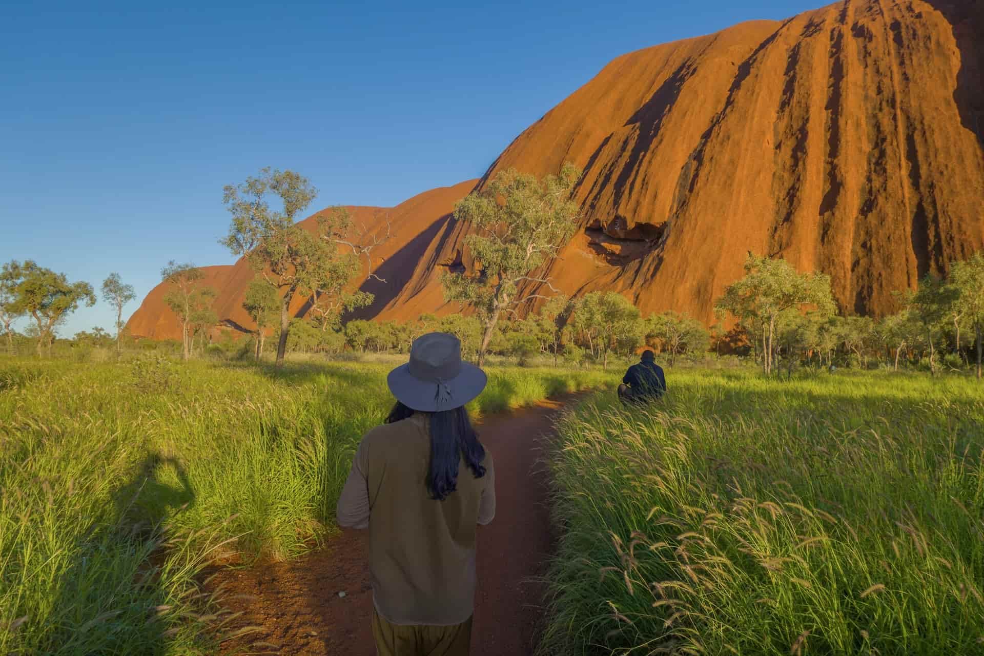 Hiker on a trail through grassland toward Uluru, Northern Territory, Australia
