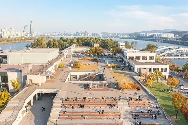 Aerial view of Nodeul Island in Seoul, featuring open-air amphitheater seating, modern buildings, and Han River views with city skyline in the background