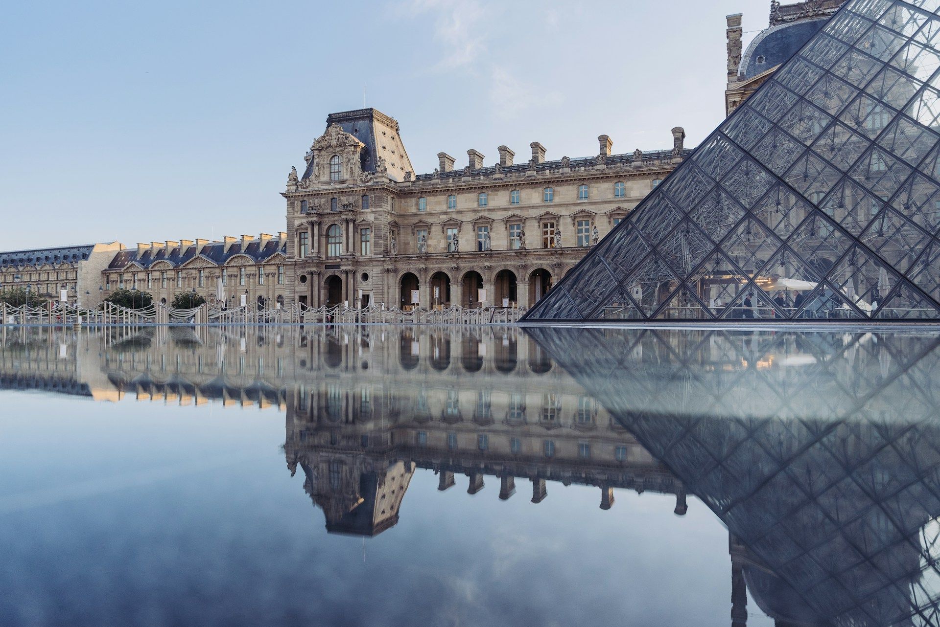 Louvre Pyramid glass structure and palace reflecting in the water, Paris