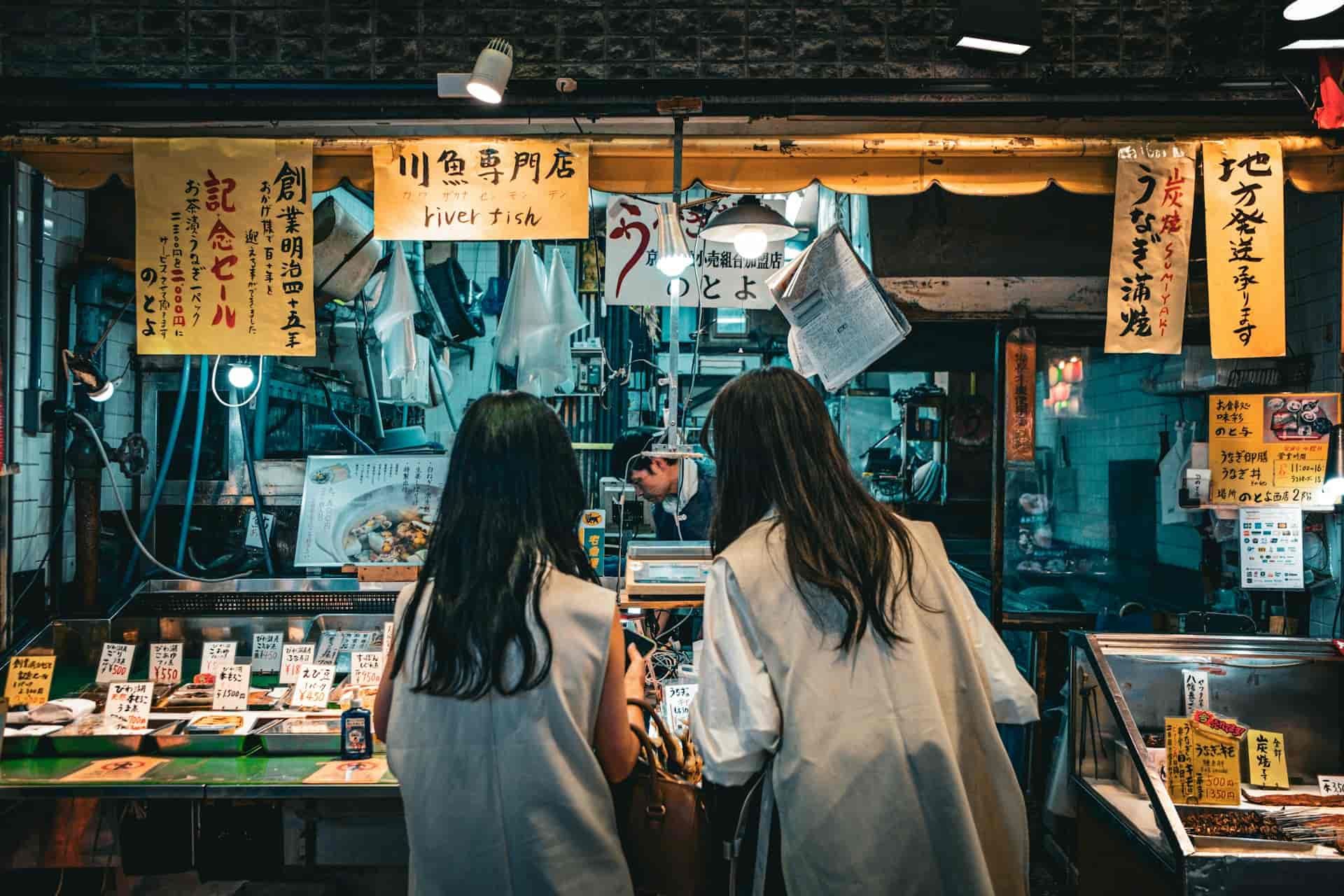 Customers ordering food at a traditional market stall in Japan