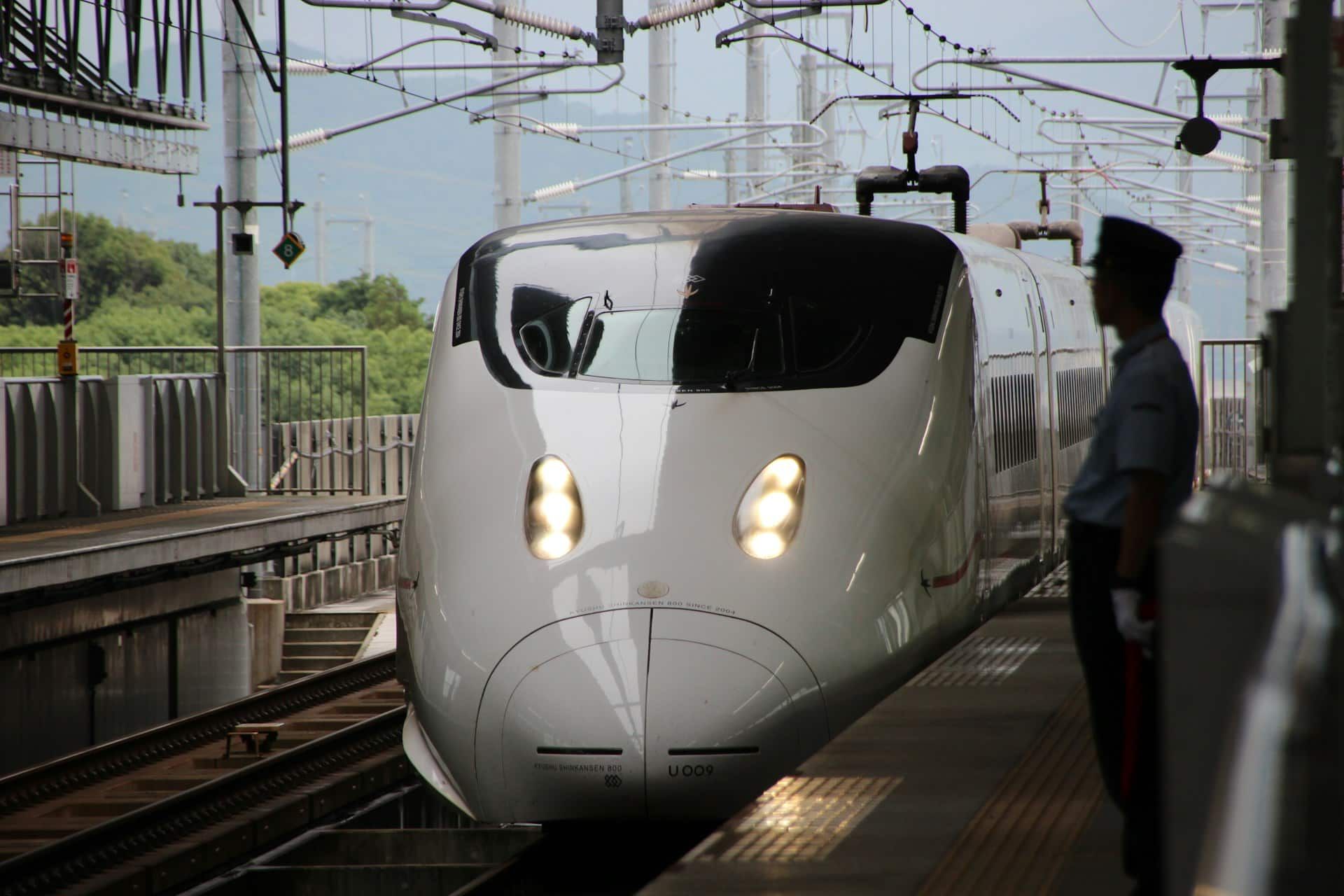 White Japan Shinkansen bullet train arriving at a station platform.