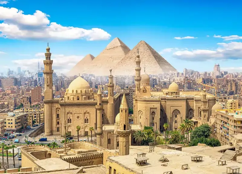 Cairo skyline with Mosque of Sultan Hassan and Pyramids of Giza in the distance, Egypt.