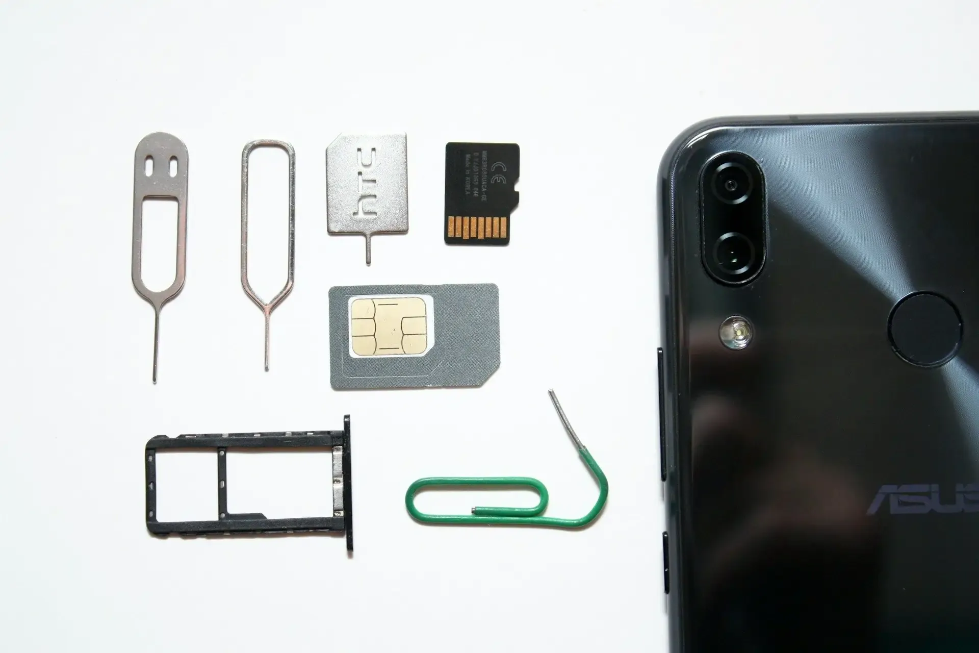 Dual SIM tools and phone components beside a smartphone.