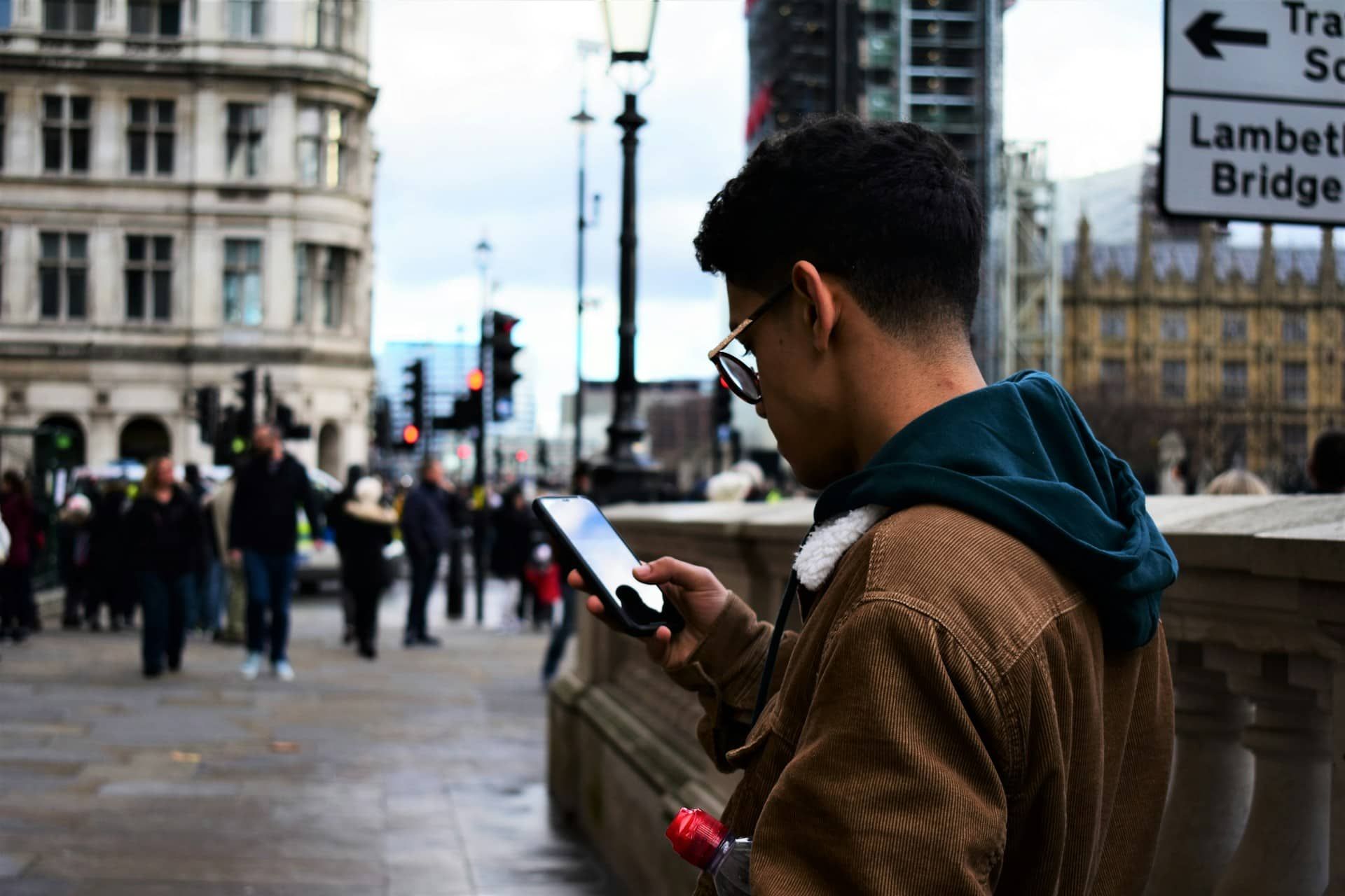 Man holding and using a smartphone in a crowd