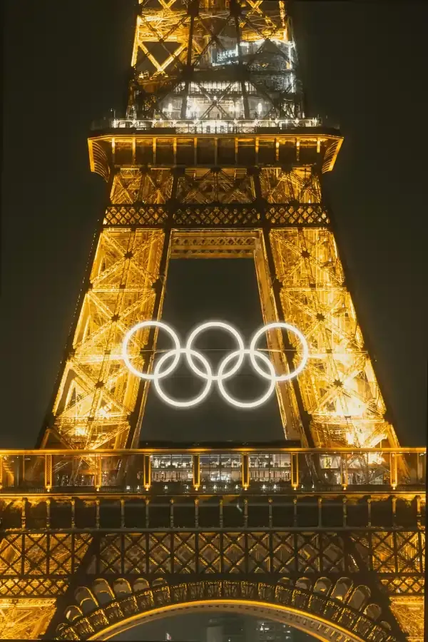 Close-up view of the illuminated Eiffel Tower at night, featuring the glowing Olympic rings displayed in the center ahead of the Paris 2024 Olympic Games.