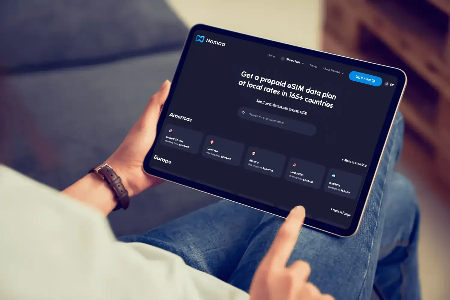 Person using an iPad to browse eSIM data plans for global connectivity on the Nomad app