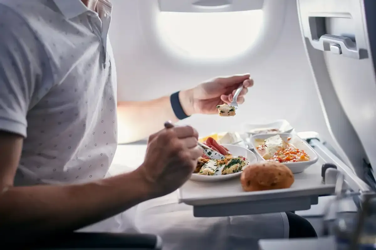 Passenger eating in-flight meal on airplane tray table