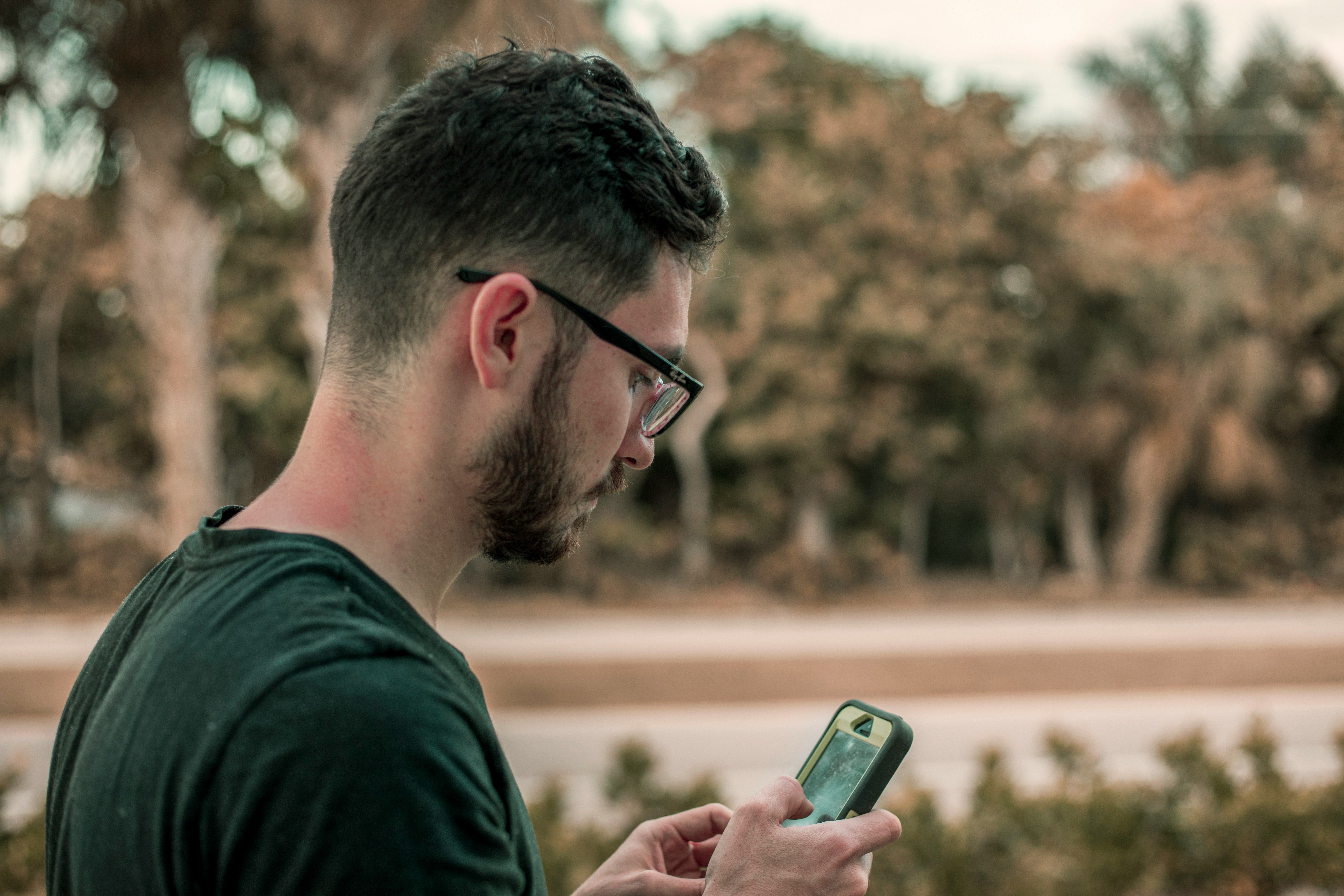 Traveler outdoors checking smartphone for signal or eSIM connectivity.