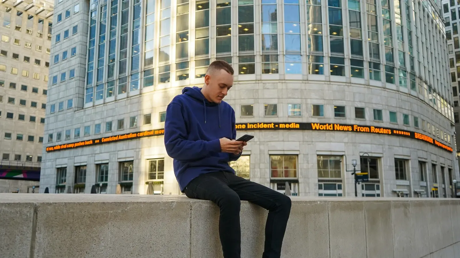 Man using a smartphone outside a modern office building in London