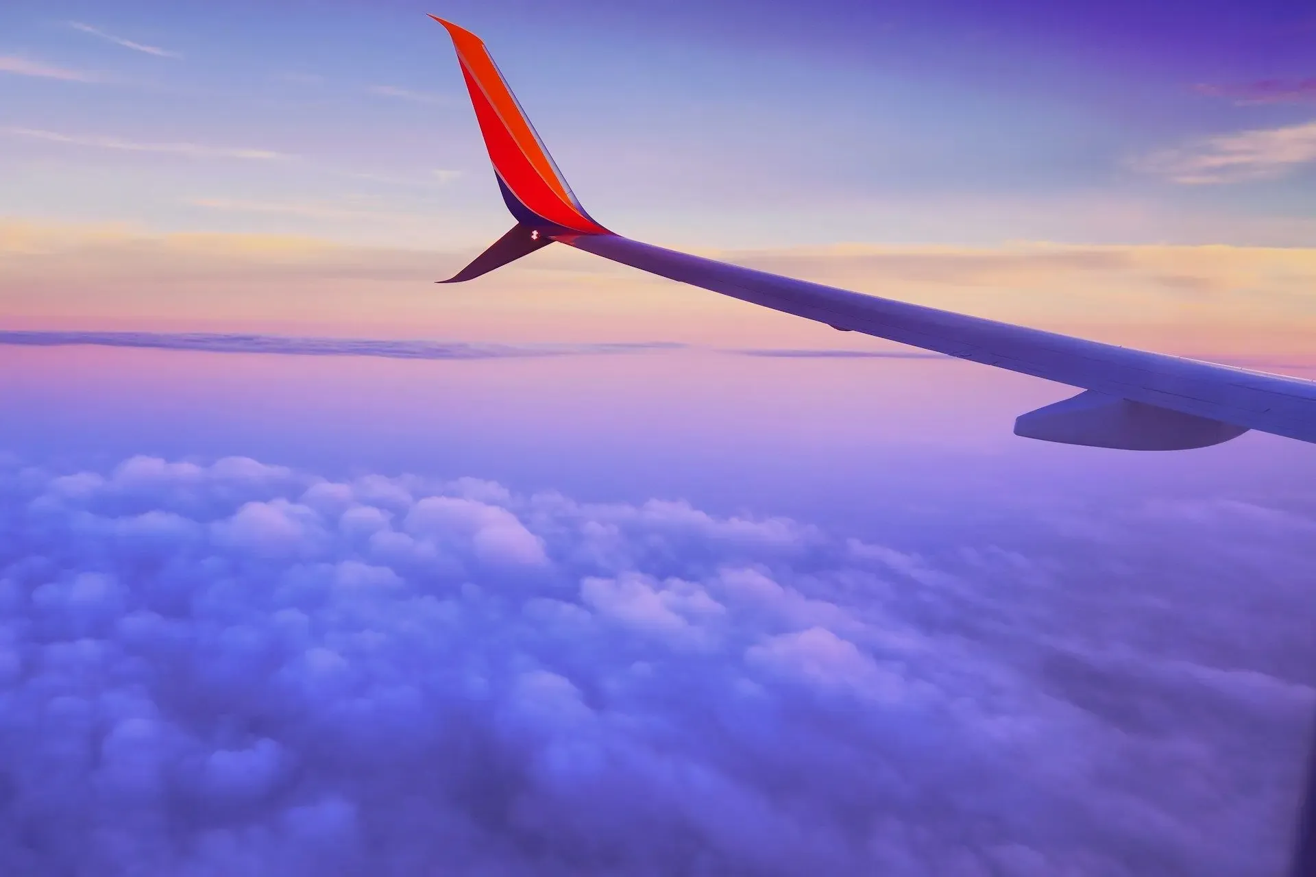 Airplane wing over clouds at sunset, representing smooth travel after booking through a third-party site