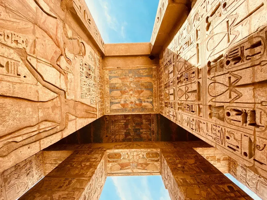 Ancient Egyptian temple walls and columns covered in carved hieroglyphs.