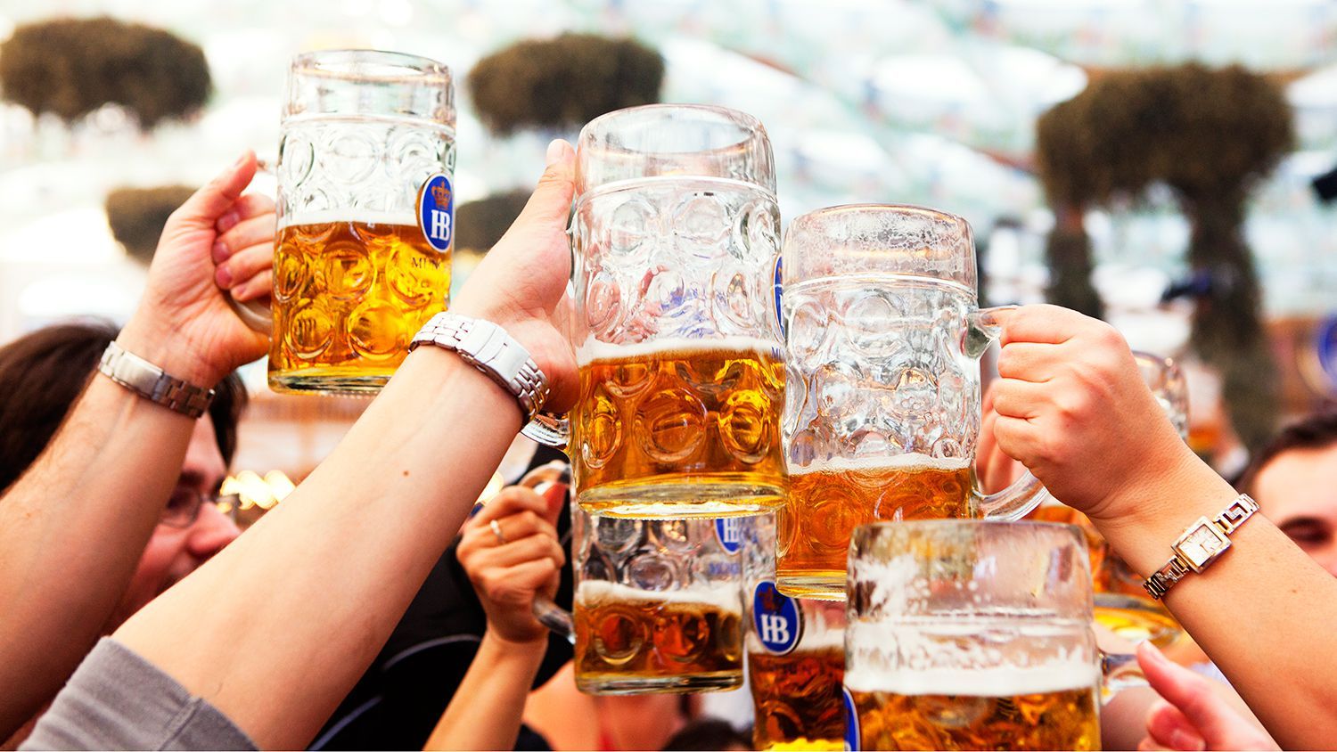 People cheering with large beer steins at Oktoberfest celebration in Munich, Germany.