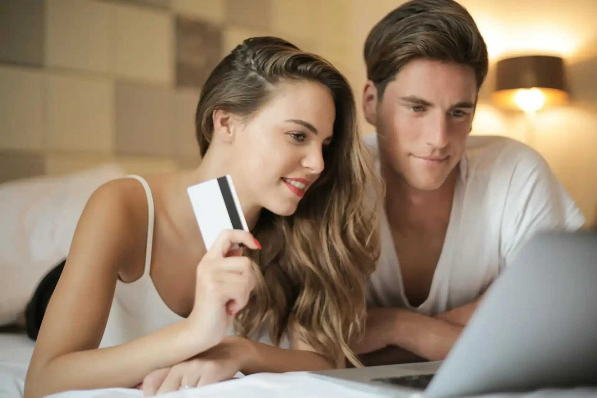 Couple buying a travel eSIM online with credit card and laptop.