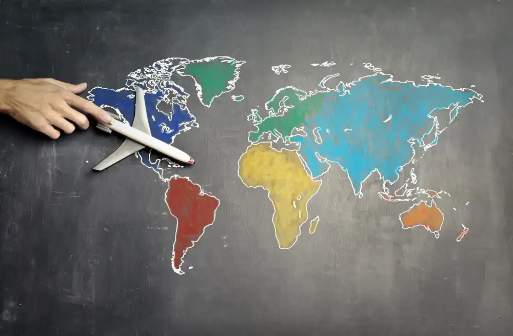 Hand holding toy airplane over world map, symbolising international travel and roaming