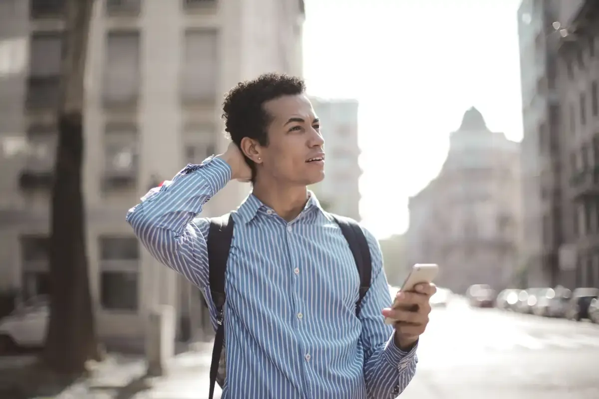 Traveller gazing around confusedly with a carrier-locked iPhone in hand, highlighting the limitations and lost connectivity of a locked iPhone.