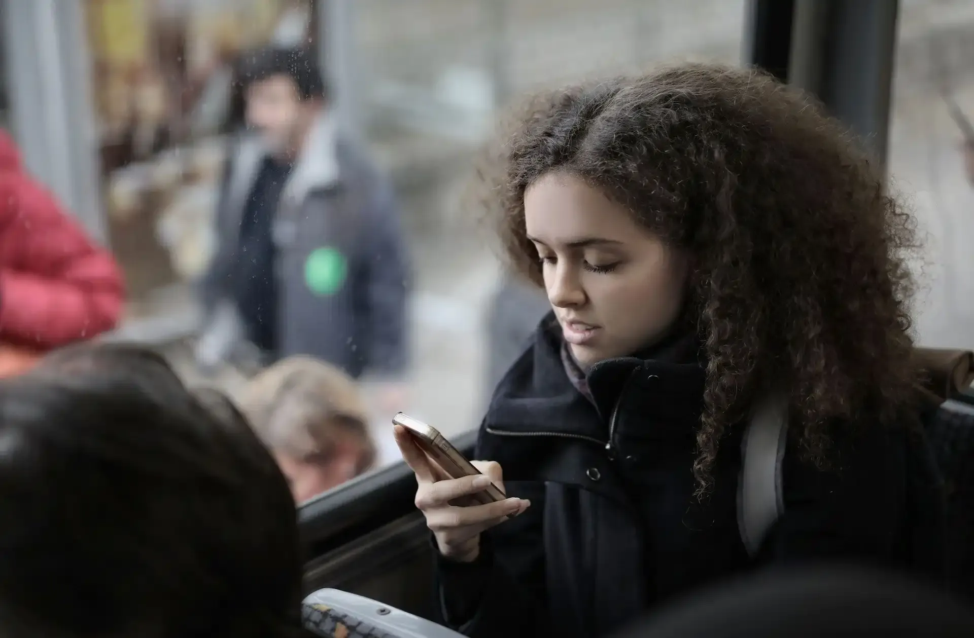 Young woman using smartphone on public transport while traveling in winter