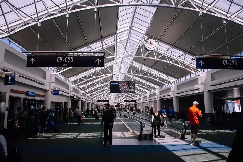 Busy airport terminal with travelers walking during a long layover near boarding gates.