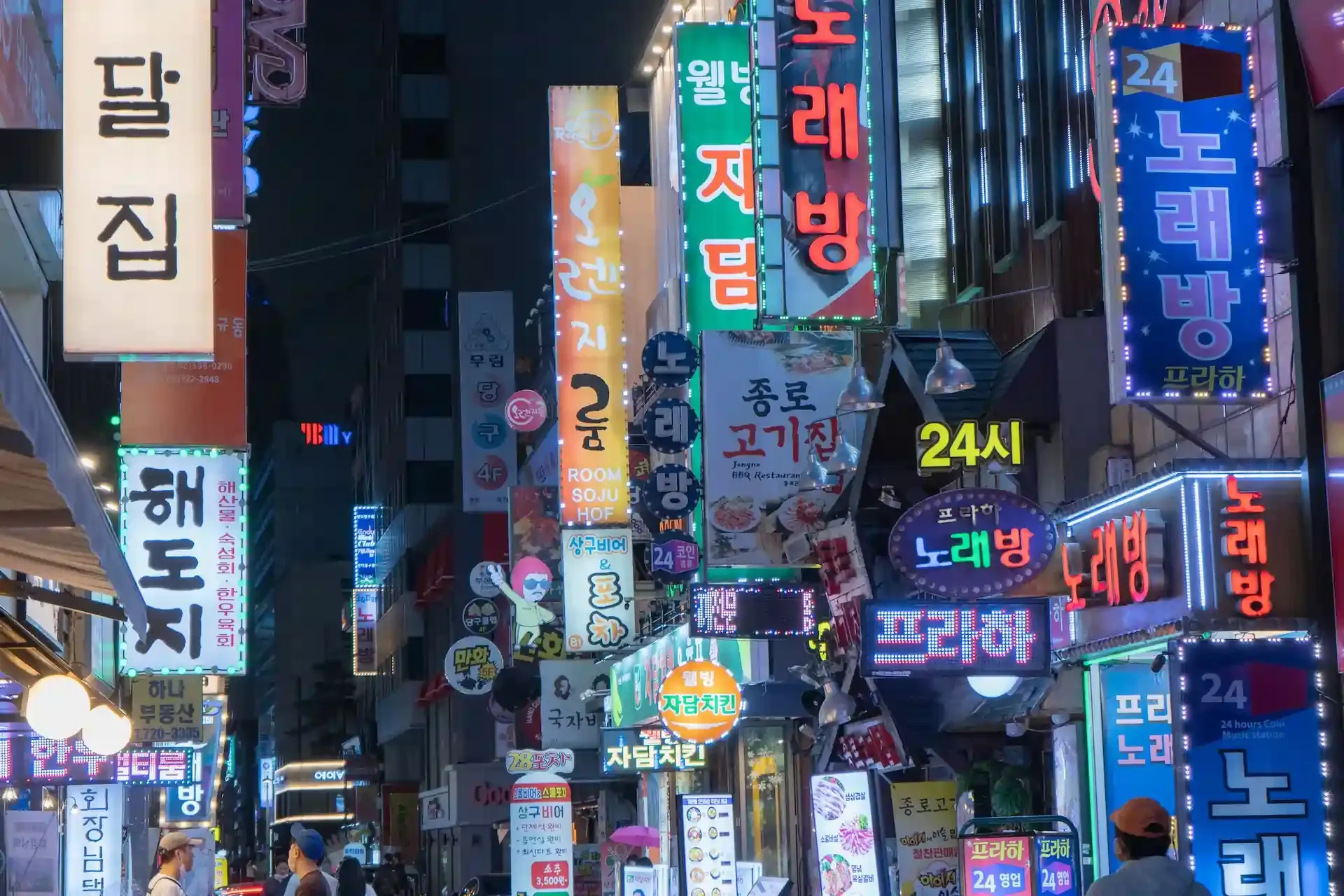 Vibrant street in South Korea illuminated with neon signs from local businesses and telecom ads, symbolizing the country’s advanced mobile network landscape.