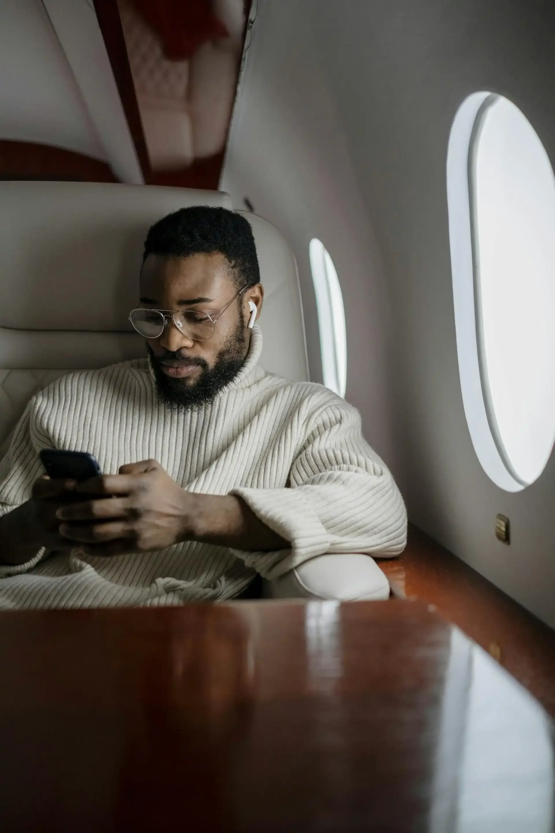 Man using smartphone and earphones while seated on a flight, illustrating in-flight internet connectivity