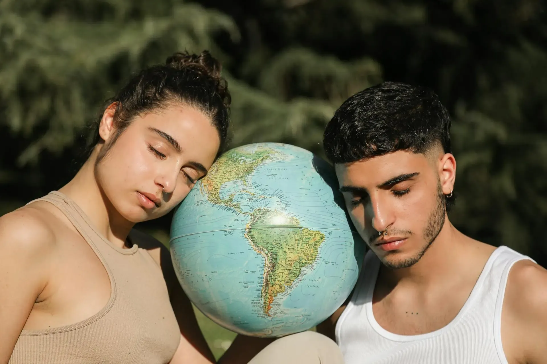 Two people resting their heads on a globe, symbolizing mindful and sustainable travel choices to reduce your carbon footprint.