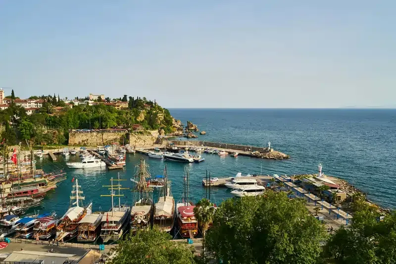 Scenic view of a marina in Antalya, Türkiye, with colorful boats and yachts docked.