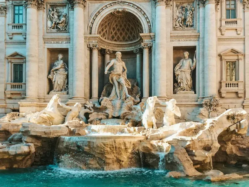 Trevi Fountain in Rome, Italy, with clear blue water and detailed Baroque sculptures under warm sunlight.