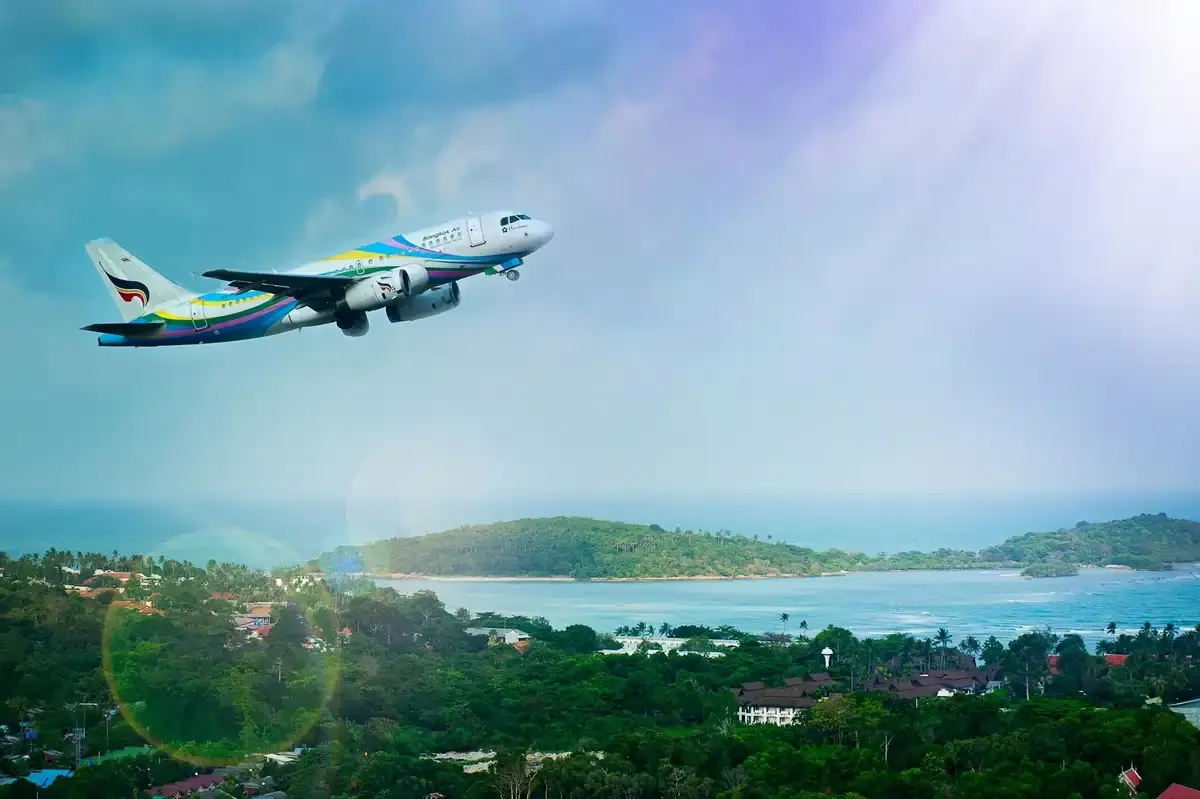 Commercial airplane flying over a tropical coastline, symbolizing open-jaw flight routes and international travel planning