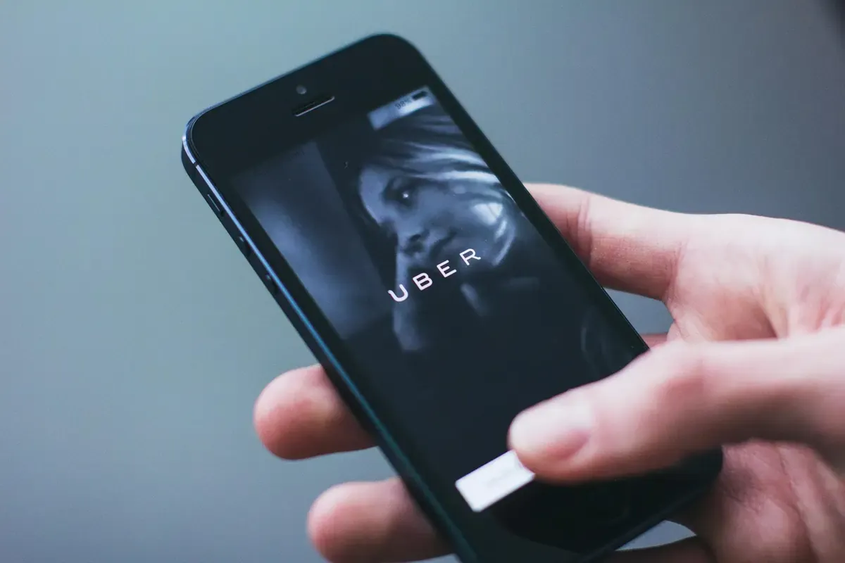 Close-up of a person using the Uber app on a smartphone, representing mobile ride-hailing while traveling.