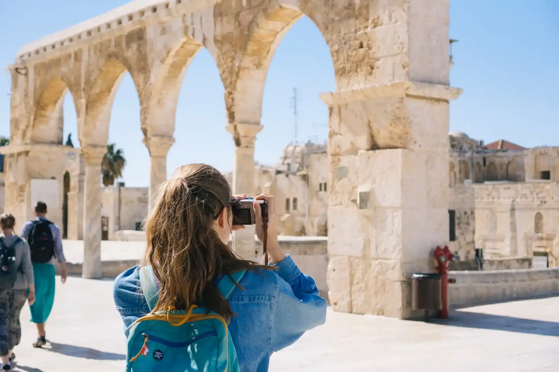 Female tourist photographing ancient stone arches while traveling.