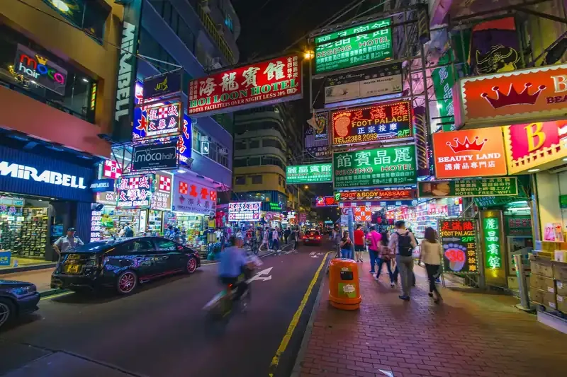 Vibrant street scene in Hong Kong at night with neon signs and bustling shops