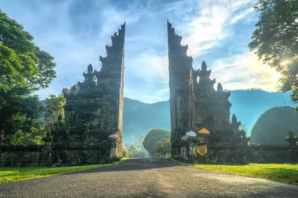 Iconic Bali temple gate at sunrise with misty mountains in the background, Indonesia travel