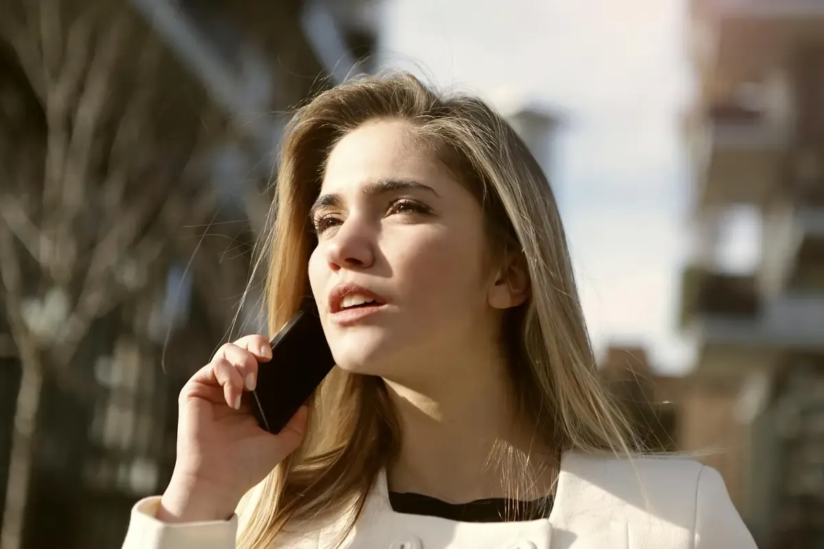 Young woman outdoors talking on her smartphone with a thoughtful expression