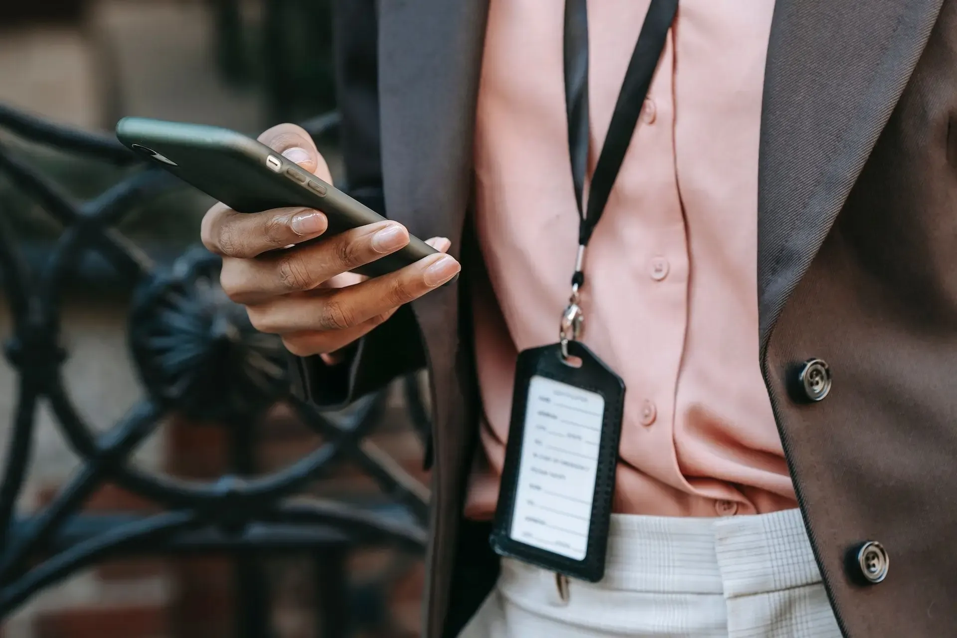 Close-up of a businesswoman’s hand holding a smartphone next to an ID badge, symbolizing eSIM naming and organization.