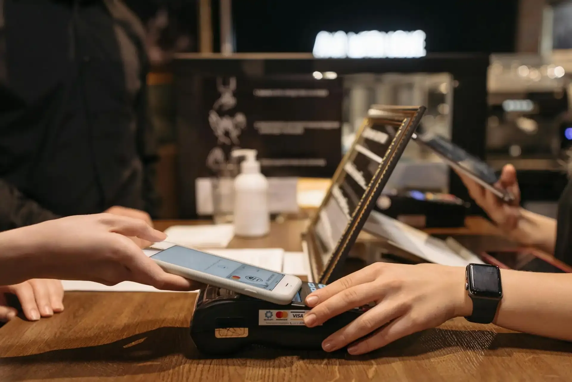 Customer making a contactless payment with smartphone at a store, using Apple Pay or Google Pay abroad