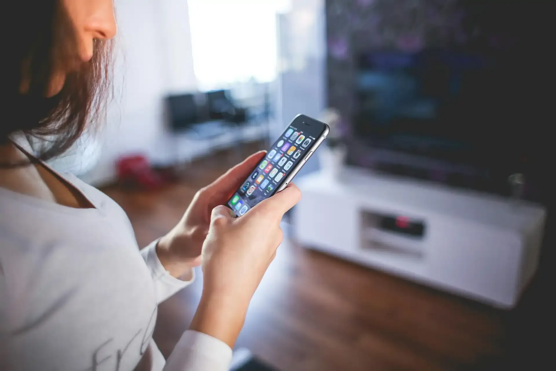 Woman in a living room holding a smartphone displaying data usage statistics, illustrating how to track mobile data usage.