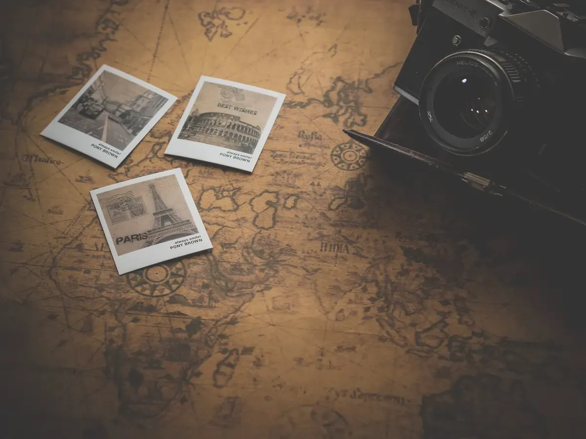 Vintage travel-themed flat lay with old camera, Europe postcards, and antique world map.
