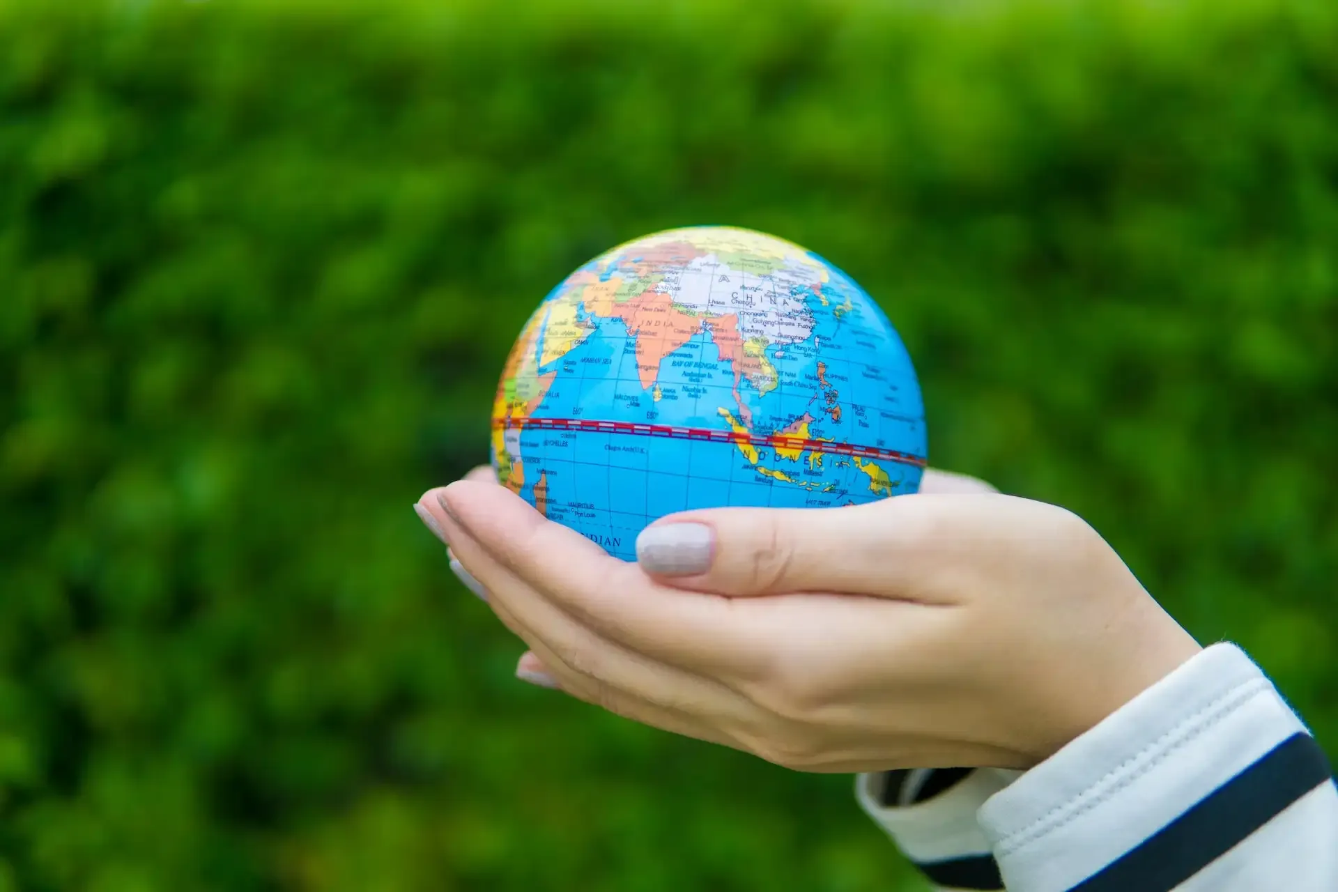 Close-up of hands gently holding a globe, symbolizing global travel and essential tips for navigating international trips smoothly.