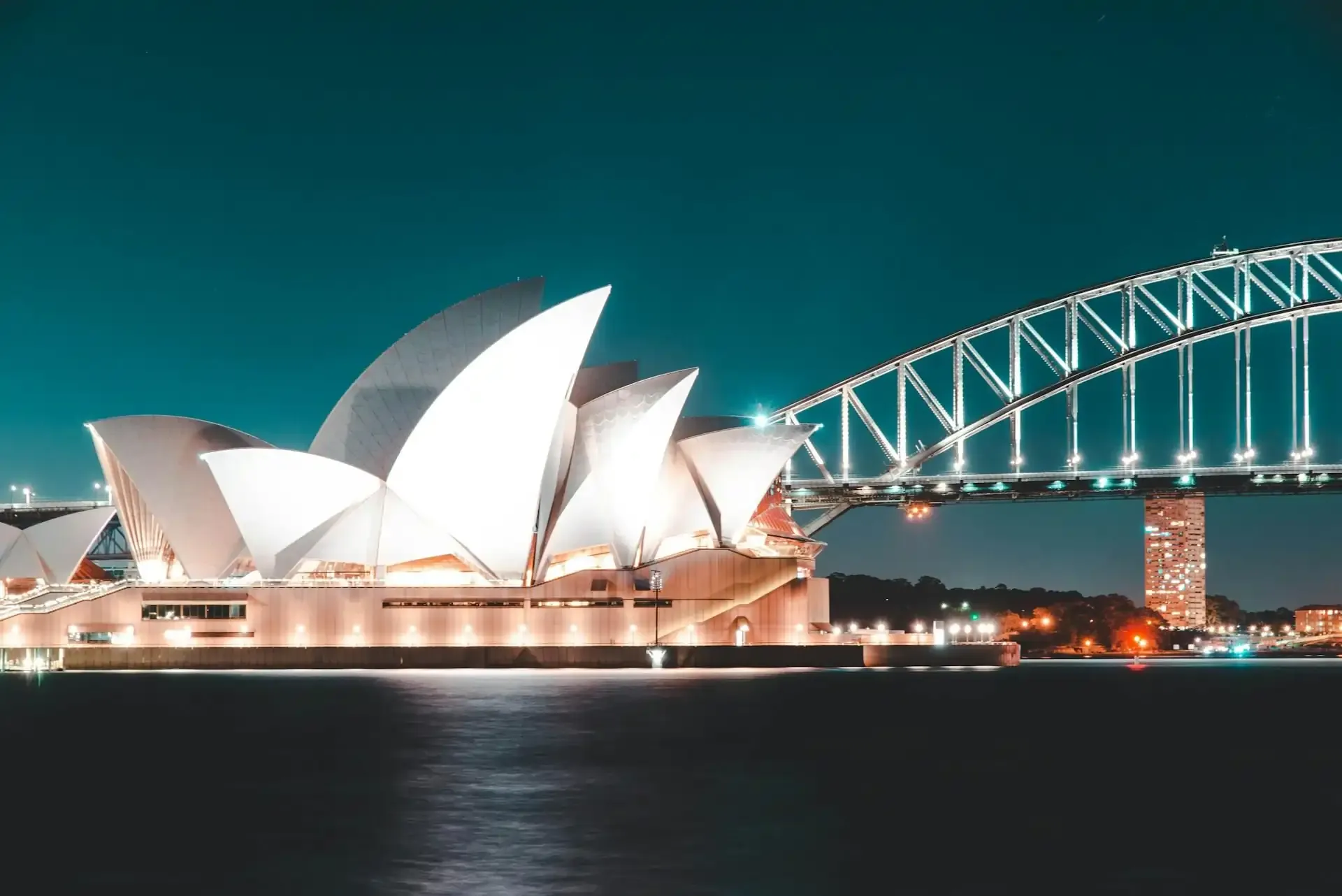 Iconic Sydney Opera House sails and Harbour Bridge aglow at night, perfect for first-timers exploring Sydney’s top attractions.