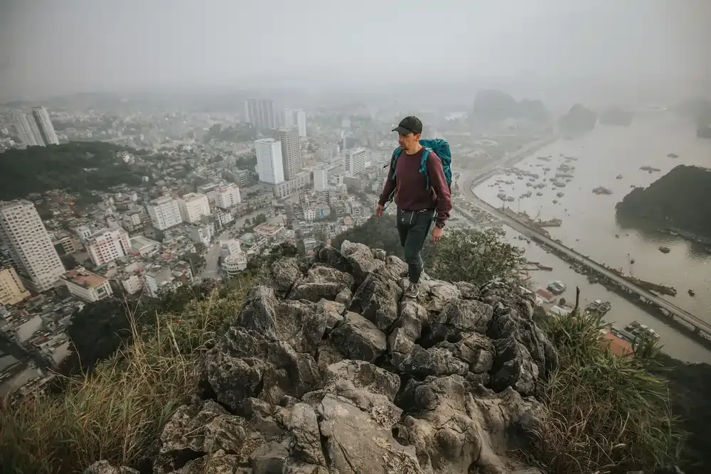 Backpacker with smartphone and gear overlooking Ha Long Bay, Vietnam.