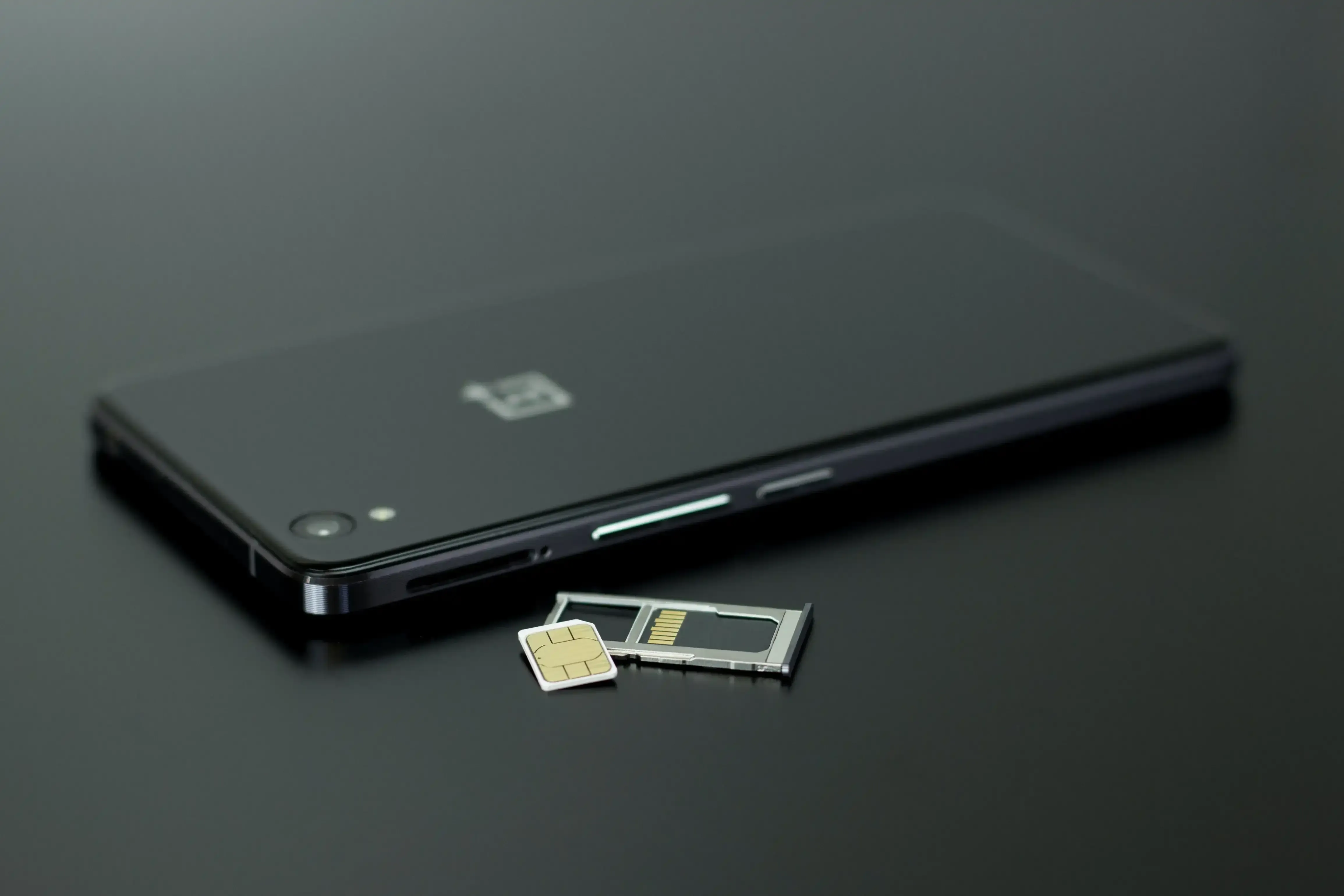 Close-up of SIM card and tray next to smartphone