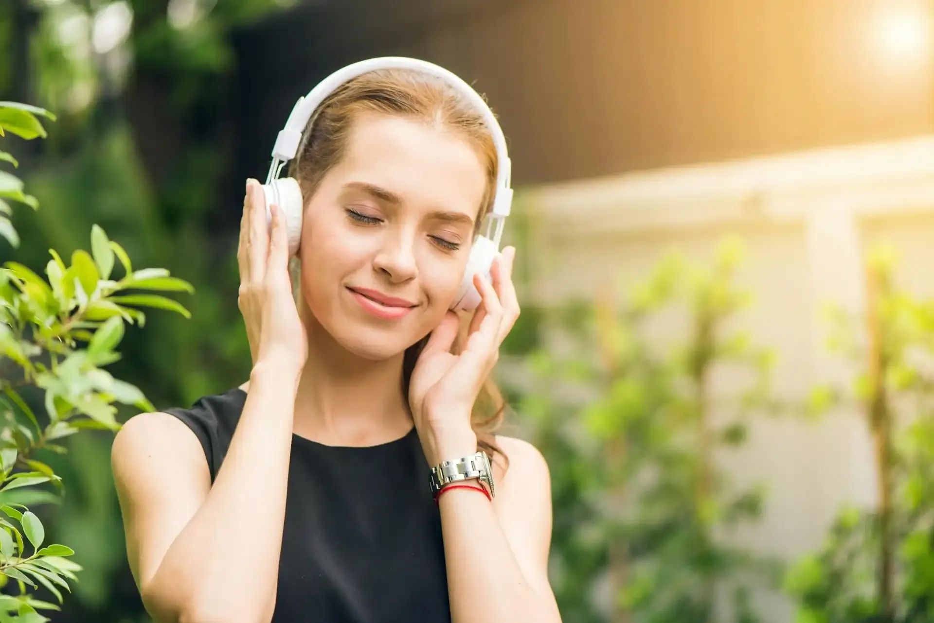 Close-up of a woman enjoying music with wireless headphones in a garden, symbolizing Spotify and Apple Music data consumption.