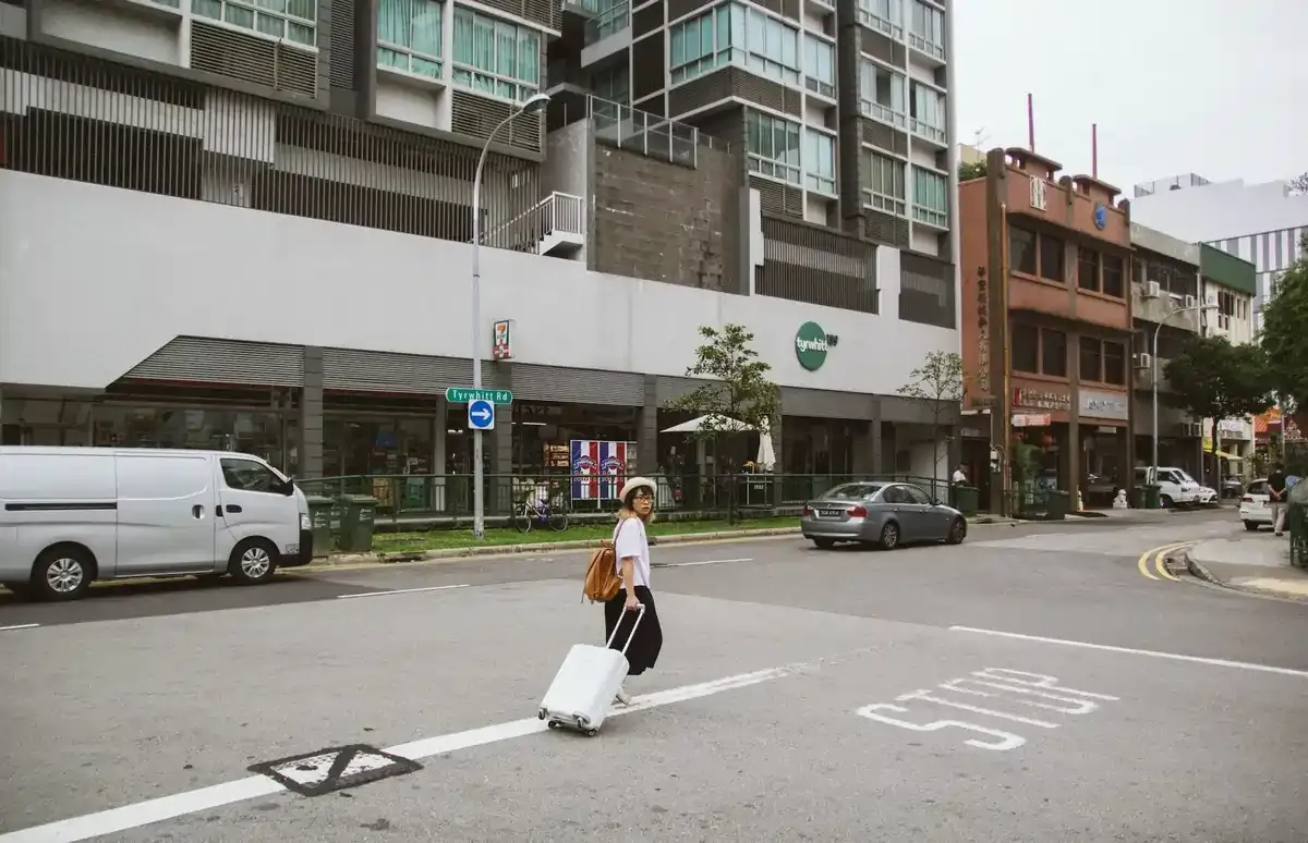 Traveler with suitcase crossing a street in Singapore’s Jalan Besar area — ideal for tourists using eSIMs or travel SIMs in Singapore and Malaysia.