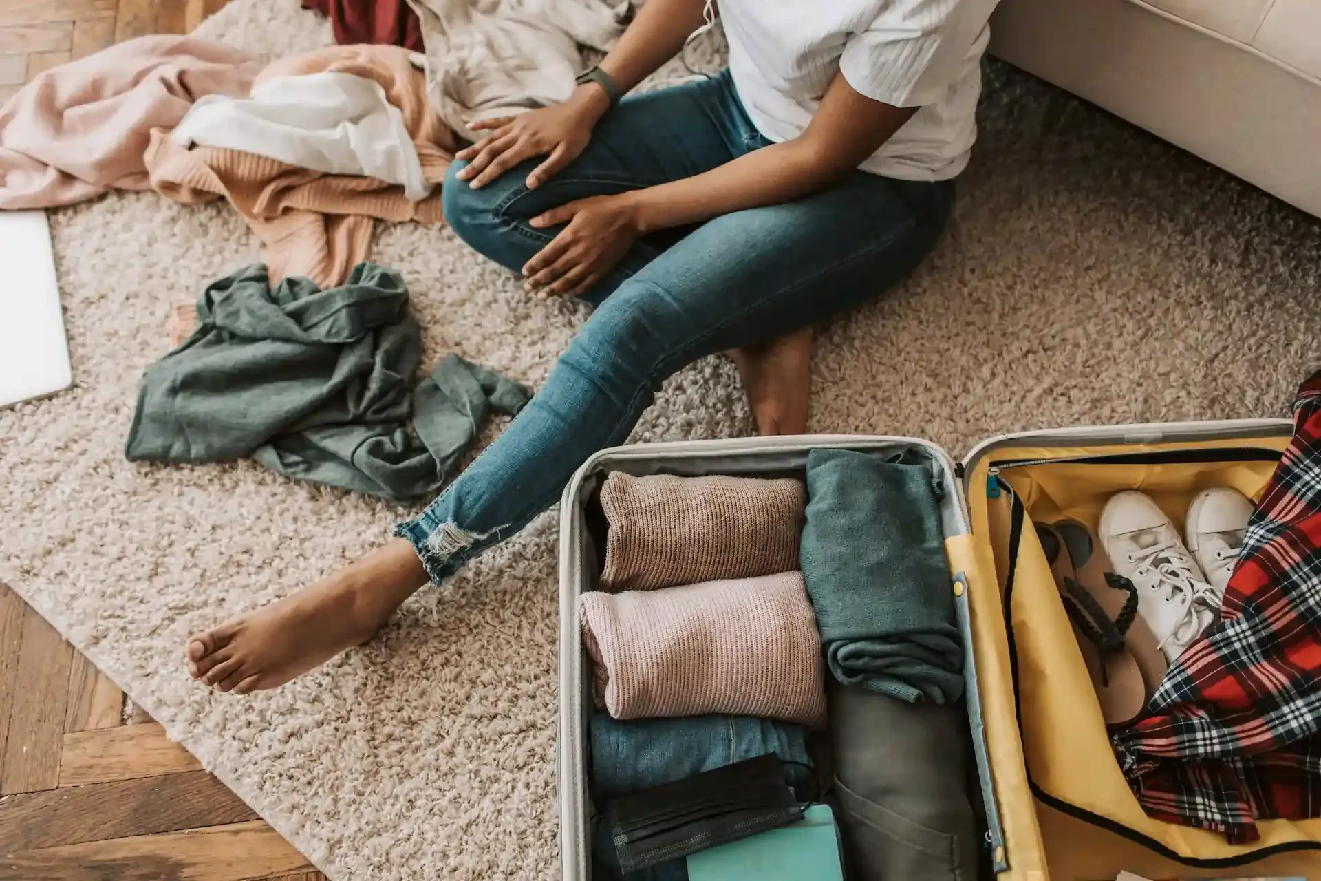 Traveler packing a suitcase with neatly folded clothes, shoes, and travel essentials, highlighting must-have items that can transform your travel experience.