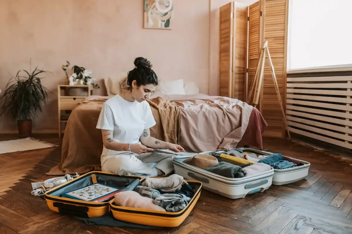 Young woman packing suitcases on the floor in a bedroom for upcoming travel