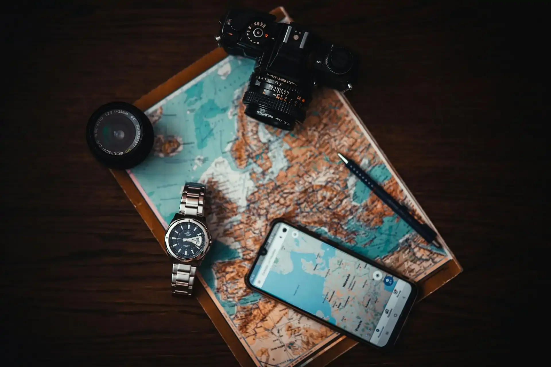 Smartphone displaying Google Maps on a paper map with a camera and watch, illustrating mobile data usage for Google Maps navigation.
