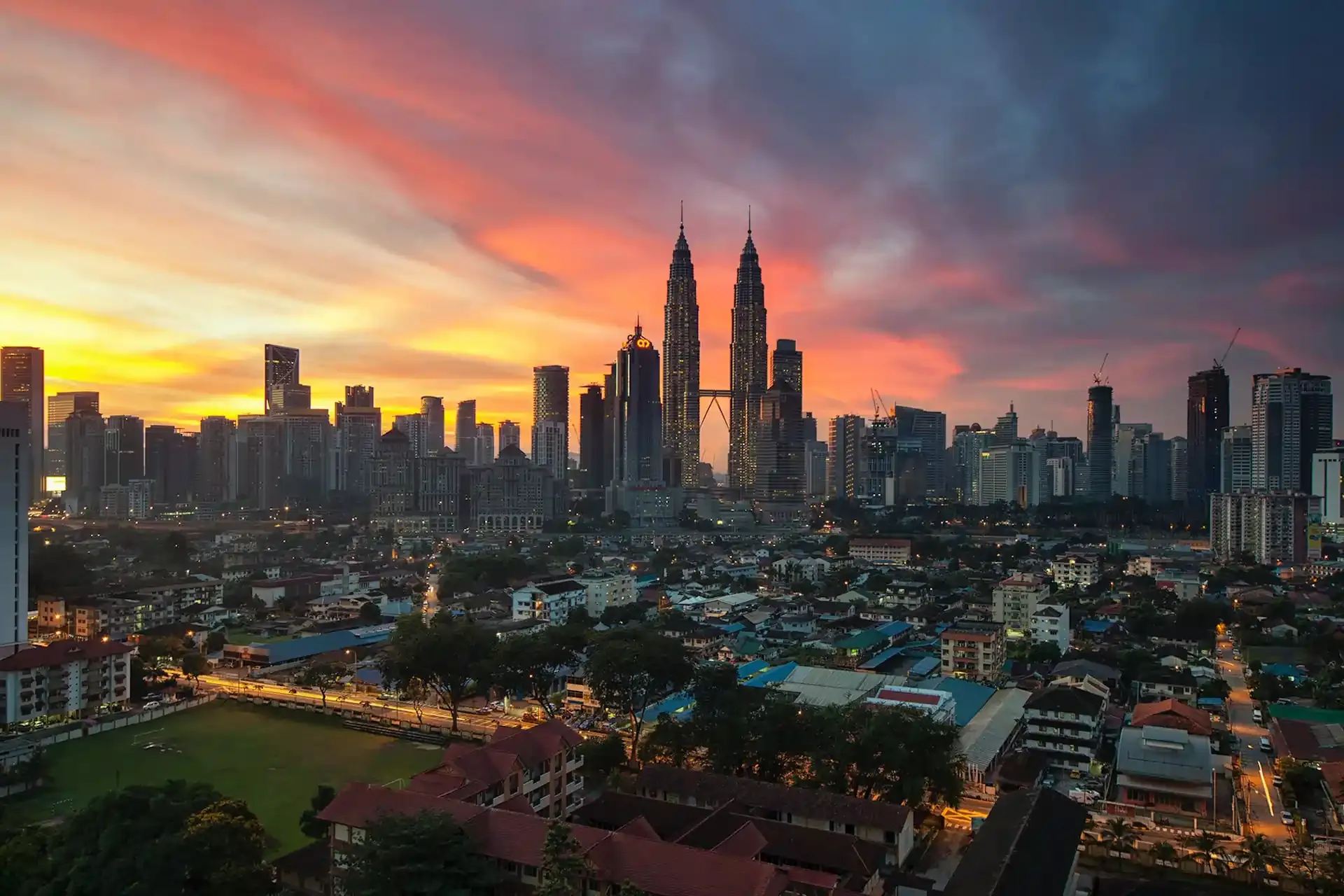 Kuala Lumpur city skyline at sunset featuring the Petronas Twin Towers, representing seamless mobile connectivity with prepaid SIM cards for travelers in Malaysia and Indonesia.